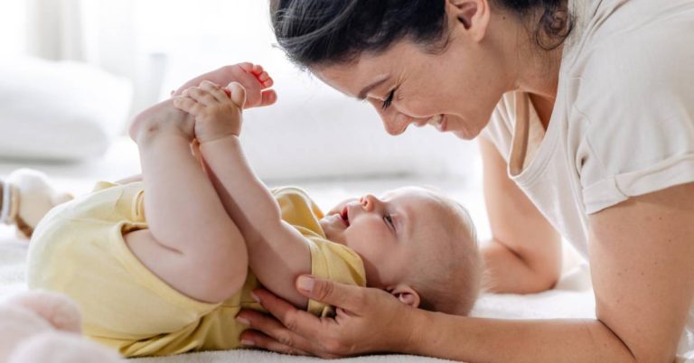 Feature post image of mom looking down at baby of the bed and connecting with baby.